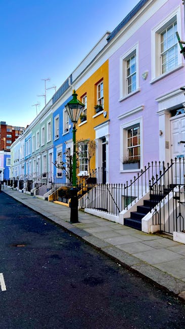 A multi-storey Victorian-style residential building with a facade of red brick and white stone detailing, featuring curved bay windows and decorative wrought iron balconies. The entrance is marked by