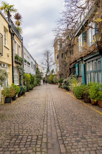 A cobbled street in South Kensington lined with residential buildings on either side. On the left, there are multi-storey houses with large windows, some with balconies decorated with potted plants an