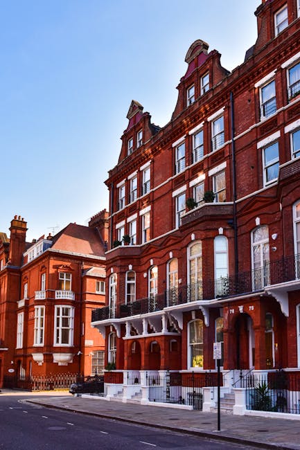 A cobbled street in South Kensington lined with residential buildings on either side. On the left, there are multi-storey houses with large windows, some with balconies decorated with potted plants an